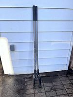 Full view of Vulcan steel post hole digger leaning against siding