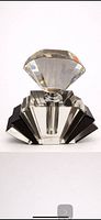 Front view of crystal perfume bottle showing diamond-cut stopper and stepped dark panels