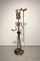 full view of metal figure sculpture with both candle platforms