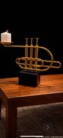 Full view of brass trumpet candleholder on table