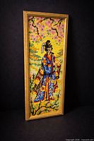 Full view of framed geisha needlepoint against dark background