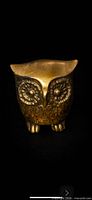 Front view of brass owl figurine showing textured eyes and feet