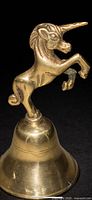 Front view of brass hand bell with unicorn finial