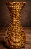 Front view of tall handwoven rattan basket vase showing full hourglass shape