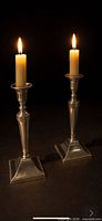 Full view of both candlesticks with lit taper candles
