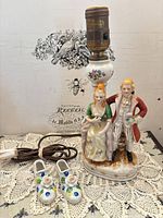 Full view of figural porcelain lamp, cord and miniature shoes