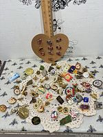 Overview of entire lot of assorted enamel pins displayed on cloth
