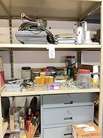 Shelves containing jars of hardware, plastic bins, tools, and 3-drawer metal organizer cabinet