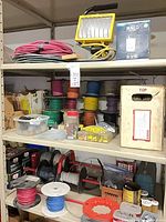shelving with multiple wire spools sorted by color, portable work light on top shelf, boxed light switch