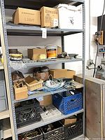 Shelf unit containing crates and boxes of mixed hardware and wiring