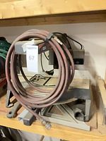 Front view of radial arm miter saw on shelf with coiled hose