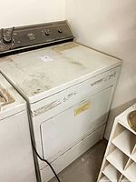 Front and top of white Whirlpool gas dryer showing paint loss and stains