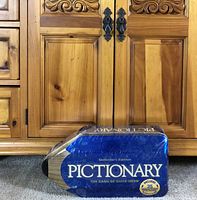 Front of sealed Pictionary tin
