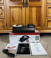 Unit on top of box with accessories laid out front: USB cable, CD, two manuals