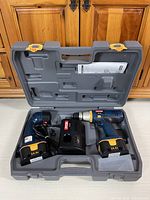 Open Ryobi case showing drill, flashlight, charger, batteries and manuals