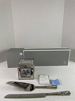 Cube picture frame, knife and server displayed in front of original gray Things Remembered box