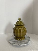 Front view of olive green ribbed cookie jar with lid