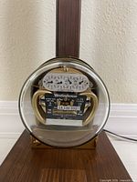 Close-up of Westinghouse residential electric meter encased in glass mounted on wood base