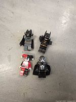Front view of four LEGO DC Comics minifigures laid out on concrete surface