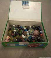Open cardboard box showing assorted marbles