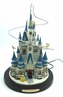 Front view of illuminated Disney Storytelling Castle showing blue turrets, character figurines, spiral track