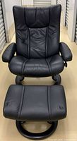 Front view of black leather Stressless recliner chair with ottoman