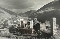 Close-up of village with stone towers and mountains