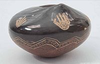 Front view showing dark burnished surface, incised handprint motifs and geometric band