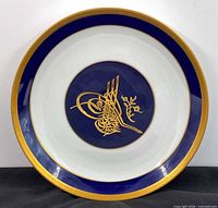 Front view of porcelain plate showing blue and gold tughra design