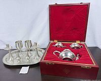 Closed case showing tea service inside and additional pewter items on tray