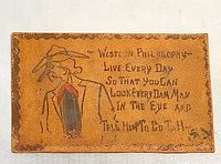 Front of leather postcard showing cowboy illustration and motto