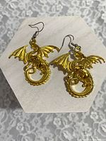 pair of goldtone dragon dangle earrings on display