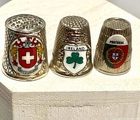 Front view of three souvenir thimbles: Switzerland, Ireland, Portugal