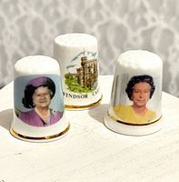 Front view of three commemorative thimbles displaying portraits and Windsor Castle graphic