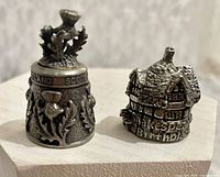 Both pewter thimbles front views showing motifs and inscriptions