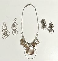 Necklace, two hoop earrings, two disc earrings on white background