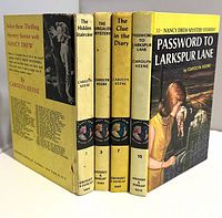 All four Nancy Drew books standing showing spines and front board of one