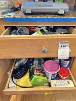 Open drawers showing mixed tools, tapes, flashlights, Dremel accessories, microfiber cloth, grey case on counter