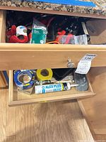 Drawer view showing multiple hand tools, tape rolls, caulk tube and cable tie pack