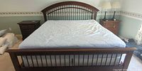 Full view of wooden king bed with pillows and linens
