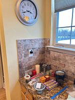 Overall view showing wall clock and assortment of candles and holders on countertop