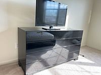 Front and right side view of black lacquer dresser with TV on top