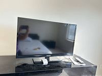 Front view of Element 32-inch TV on stand with remote visible
