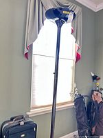 Full view of torchiere floor lamp standing next to luggage for scale