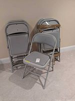 Stack of grey metal folding chairs, one opened to show seat and back padding