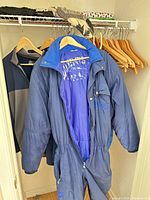 Multiple jackets hanging; front Luhta blue ski suit and grey/navy jacket visible