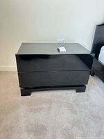 Front view of one nightstand showing glossy black finish and two-drawer layout