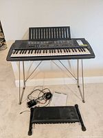 Keyboard on stand with bench seat, cables and manual visible