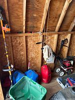 Overall view showing weed trimmer, fuel cans, rototiller and part of spreader