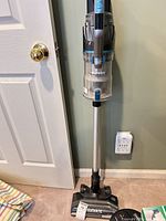 Full view of upright Eureka Elevate stick vacuum against wall